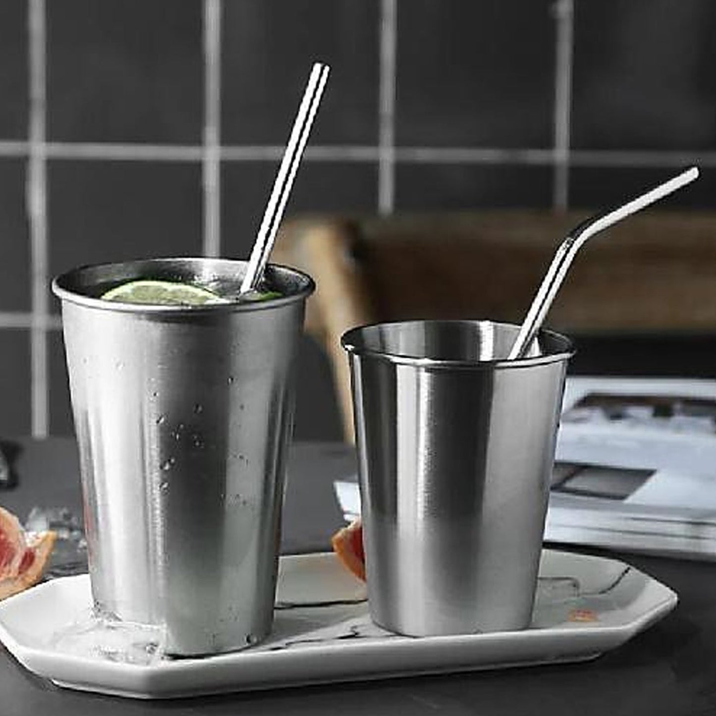 Staright and bent Reusable metal straw in a stainless steel glass placed on a tray