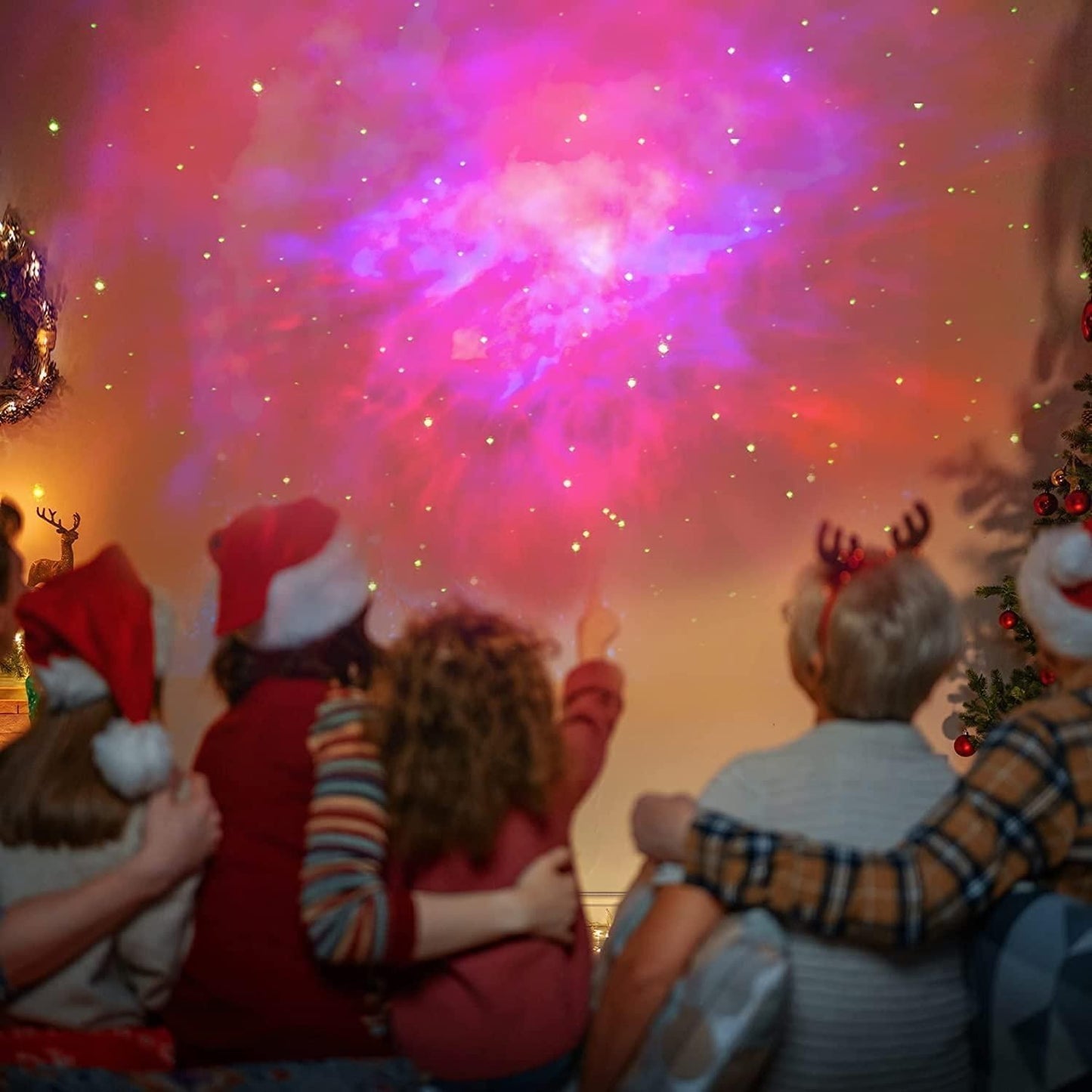 People wearing festive hats and reindeer antlers watching fireworks.