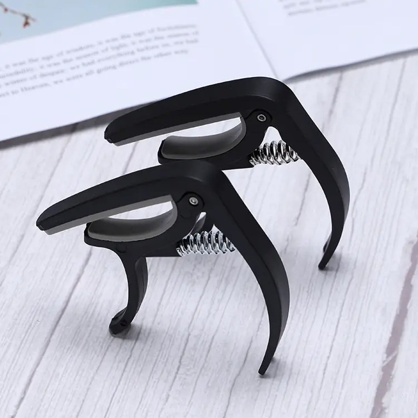 Adjustable guitar capo made from durable plastic, compatible with multiple string instruments
