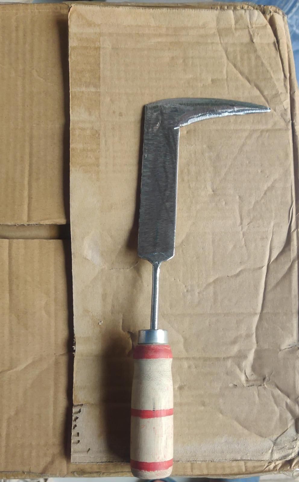 Gouge tool with wooden handle on a cardboard background. Manual stainless steel weed puller displaying handheld ergonomics and arc blade cutting edge detail