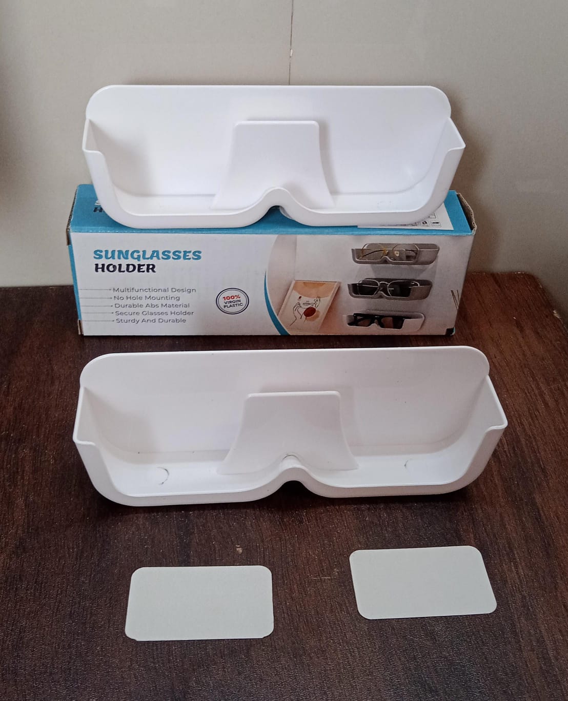 Plastic eyeglass storage holder mounted on smooth surface