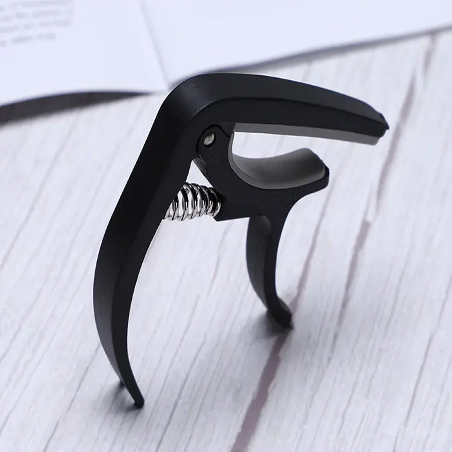 Soft plastic guitar capo designed to protect strings while providing reliable clamping pressure