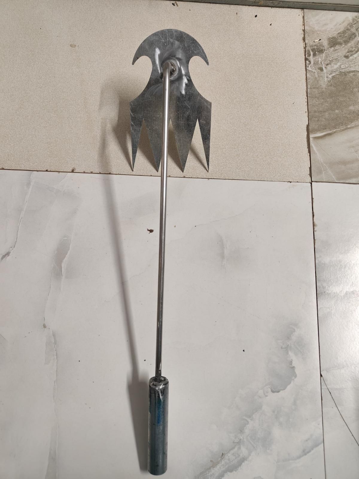 Metal tool with a curved blade and handle on a tiled floor, Weeding puller with sharp metal construction displaying compact size perfect for garden weed removal