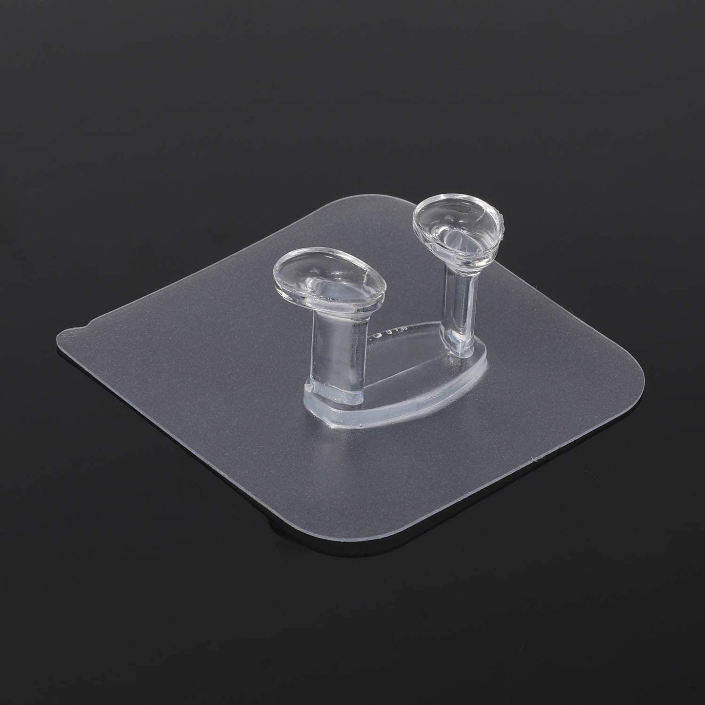 Transparent self adhesive hook mounted on white wall surface