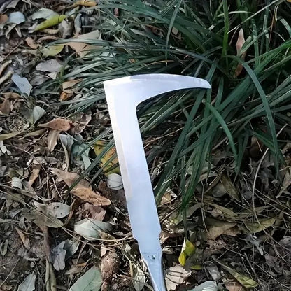 White curved blade on a ground with grass and leaves. Handheld arc weeding tool with stainless steel construction and wooden handle showing 31.8cm professional design