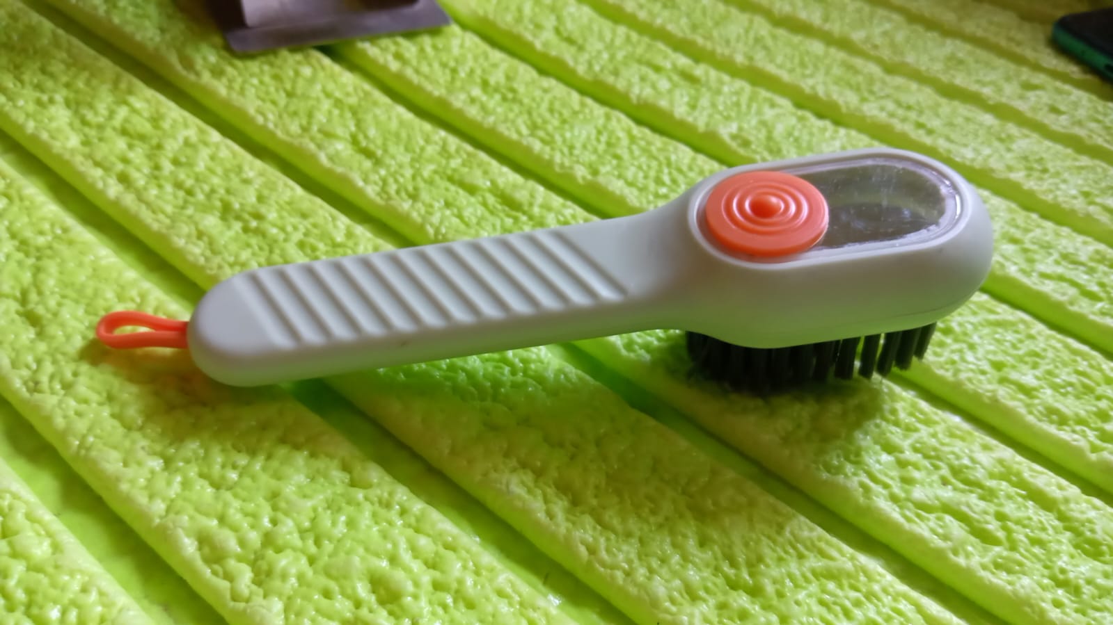 Scrubbing brush with counter-top storage cord and bristle head
