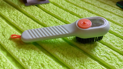 Scrubbing brush with counter-top storage cord and bristle head