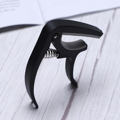 Soft plastic guitar capo designed to protect strings while providing reliable clamping pressure