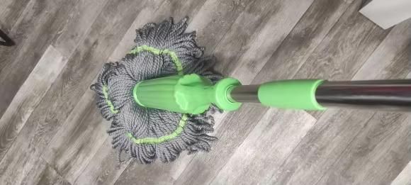 Mop with a green handle cleaning a wooden floor, Steel handle rotating mop with push-to-clean dry self twisting system for effortless floor cleaning